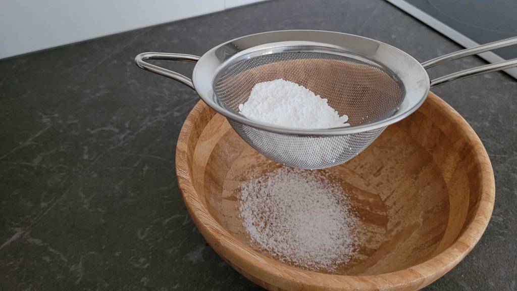 Küchensieb im Test: Edelstahl-Küchensieb inklusive Puderzucker über einer Holzschüssel mit gesiebten Puderzucker.