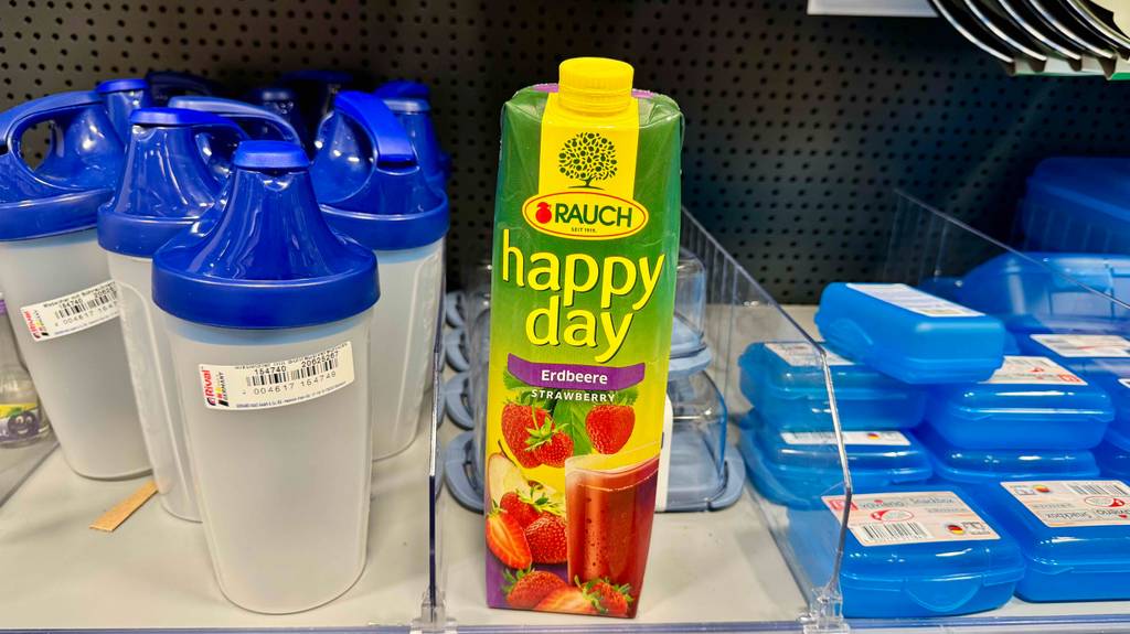 Happy-Day-Saft im Test: Ein Tetrapak der Firma Rauch steht in einem Regal mit Aufbewahrungsdosen.