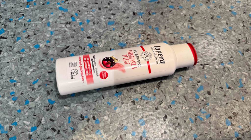Eine weiße Kunststoffflasche mit Lavera-Shampoo im Test liegt auf einem Linoleumboden.