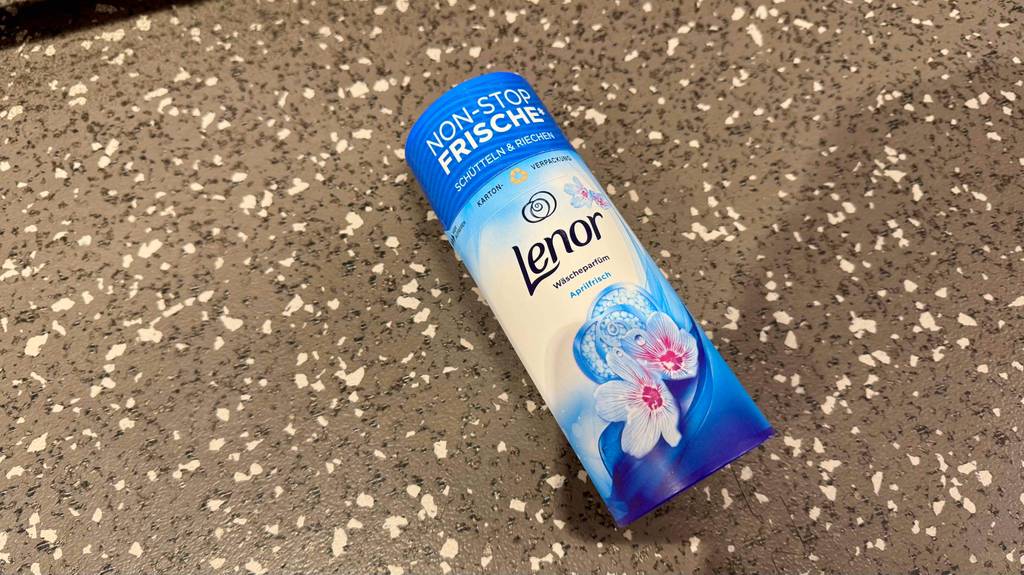 Das getestete Lenor-Wäscheparfüm liegt in seiner Karton-Verpackung auf dem Boden.