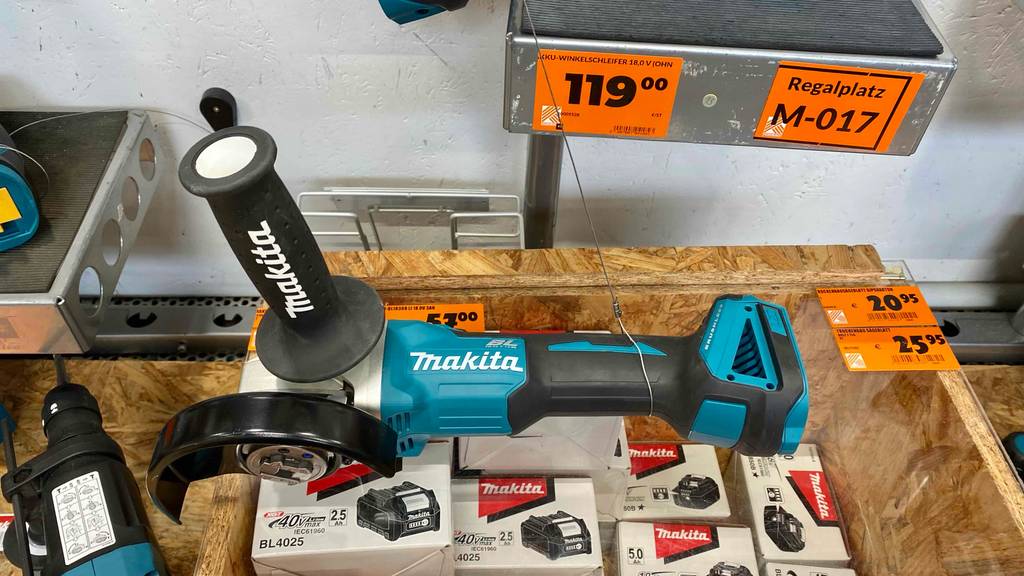 Ansicht von oben auf einen türkis-schwarzen Makita-Akku-Winkelschleifer im Test, der auf einer Kiste mit passenden Akkus liegt.
