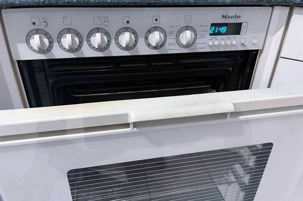 Getesteter Backofen von Miele: Nahaufnahme des Bedienpaneels sowie leicht geöffnete Backofentür.