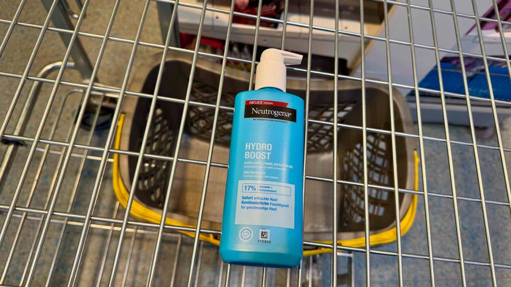 Neutrogena-Bodylotion im Test befindet sich in einem blauen Spender im Einkaufskorb eines Drogeriemarktes.