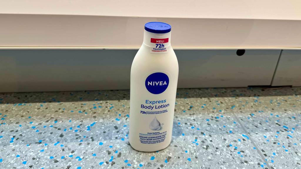 Eine weiße Flasche mit Nivea-Bodylotion im Test steht auf einem Fliesenboden.