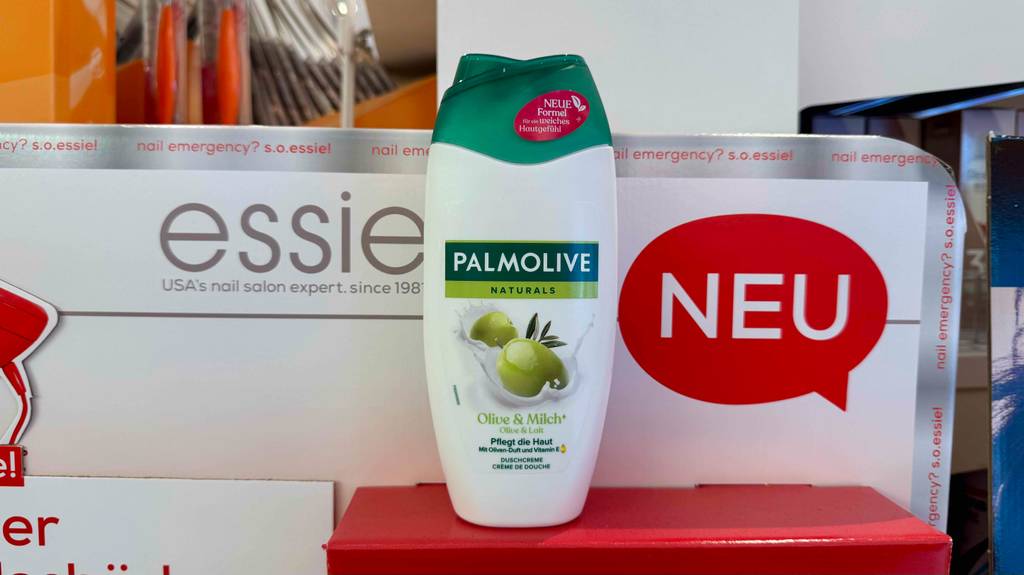Eine Quetschflasche mit getestetem Palmolive Duschgel steht auf einem roten Karton.
