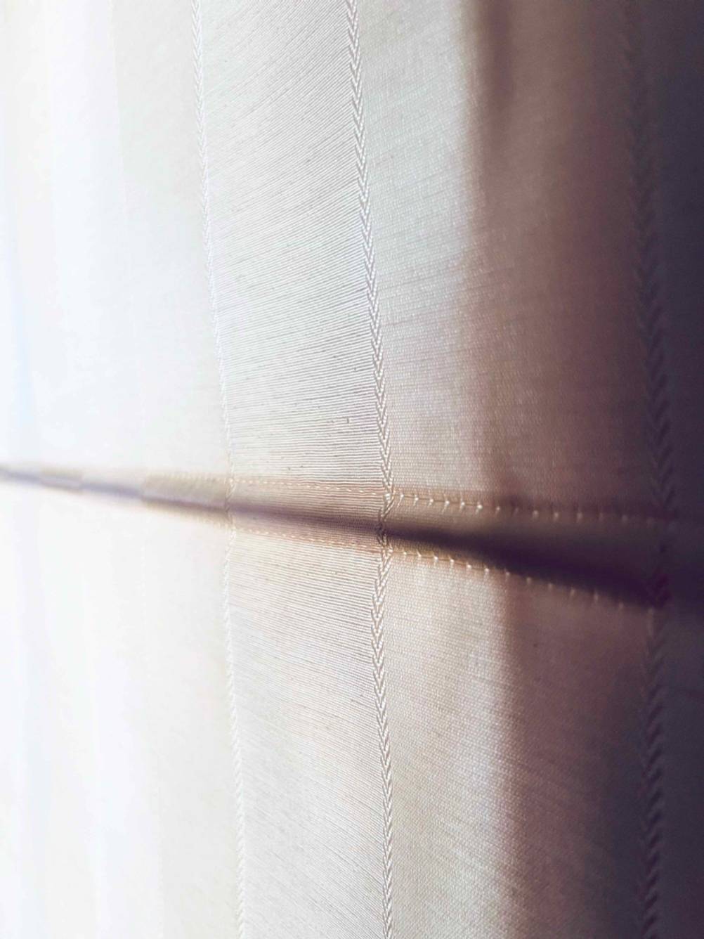 Detailansicht der steifen, horizontalen Verstrebungen, versteckt im weißen Stoff eines getesteten Raffrollos.