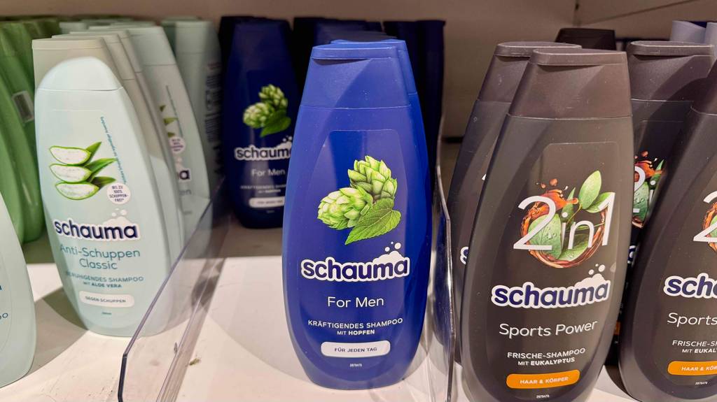 Schauma-Shampoo für Männer im Test: Eine blaue Quetschflasche mit Shampoo steht in einem Regal mit anderen Shampoosorten.