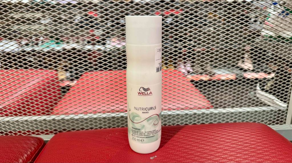 Ein getestetes Wella-Shampoo in der weißen Kunststoffflasche steht auf einem roten Hocker im Geschäft.