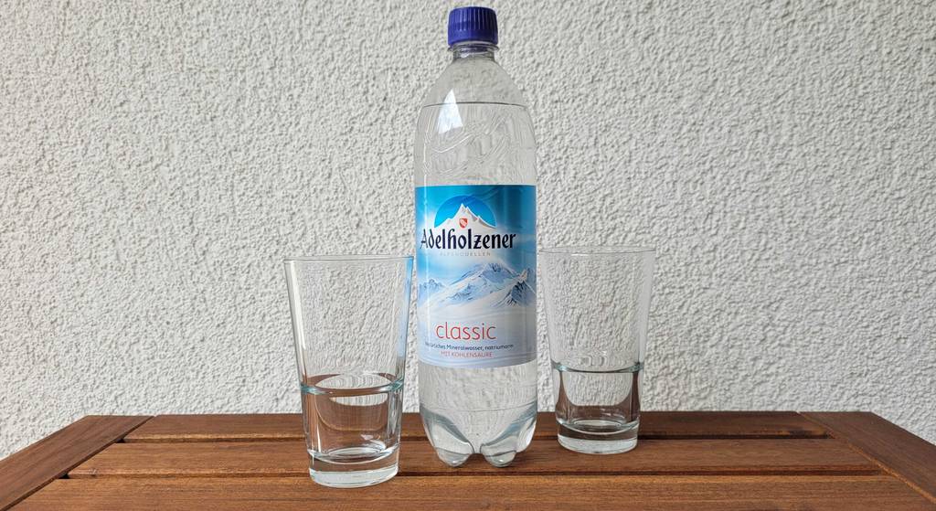 Im Test: Adelholzener Wasser in der Kunststoffflasche steht zwischen zwei Gläsern.