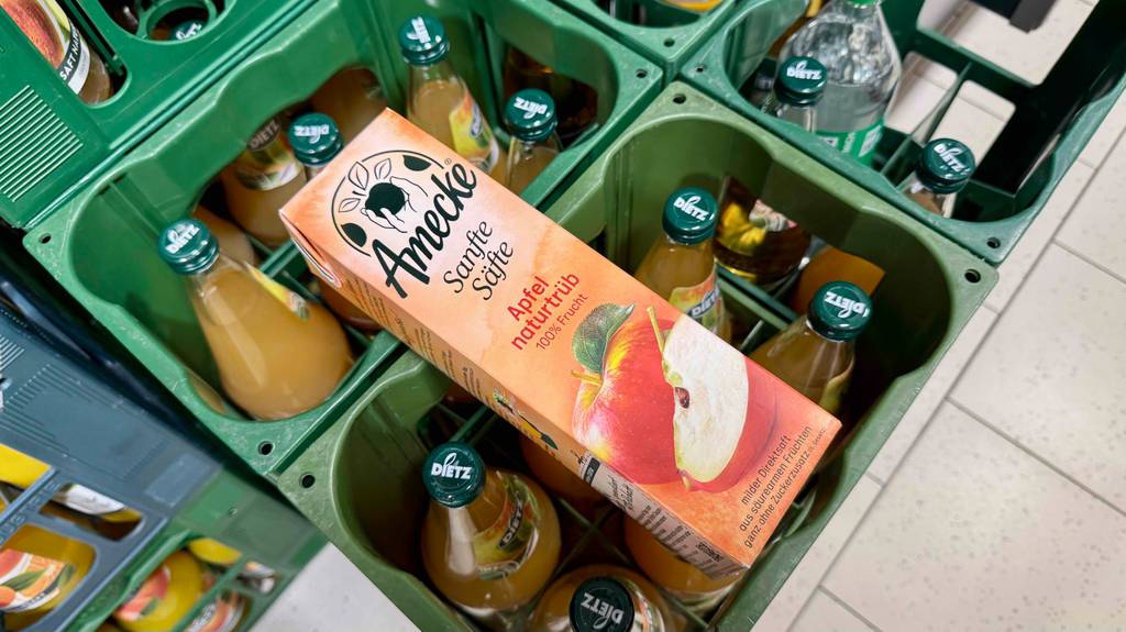 Getestet: Naturtrüber Apfelsaft im Tetrapak liegt auf Kästen mit Glasflaschen.