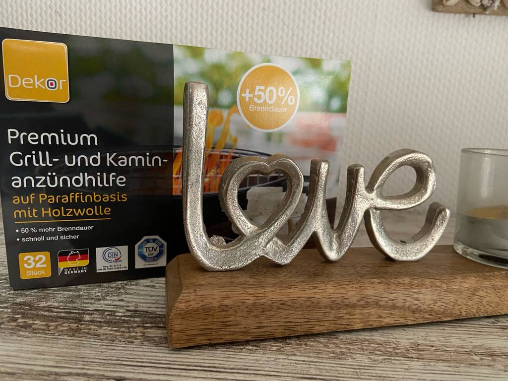 Anzünder Test: Eine Packung Grill- und Kaminzündhilfe steht neben einer Dekoration auf einem Holztisch.