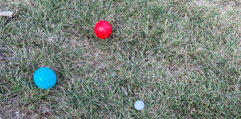 Getestete Boule aus Kunststoff liegen auf Gras in der Nähe der weißen Zielkugel.