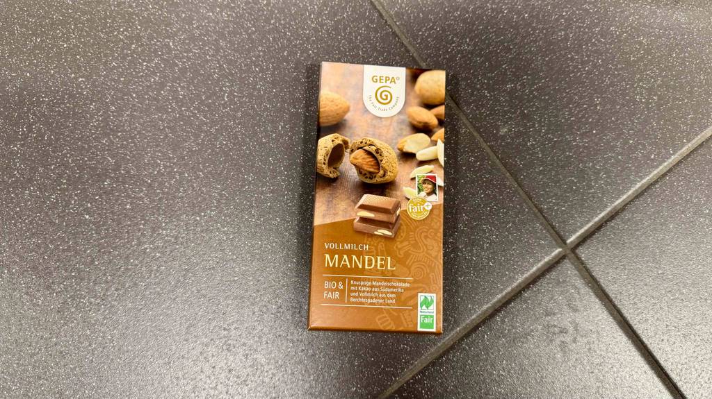 GEPA-Schokoladen-Test: Eine Tafel Schokolade mit Vollmilch-Mandel-Geschmack liegt auf einem grauen Fliesenboden.