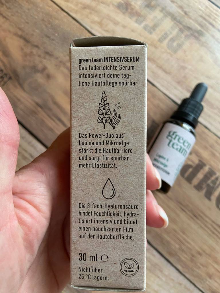 In einer Hand liegt die Verpackung der Glättungscreme im Test, der Fokus liegt auf der gedruckten Produktbeschreibung.