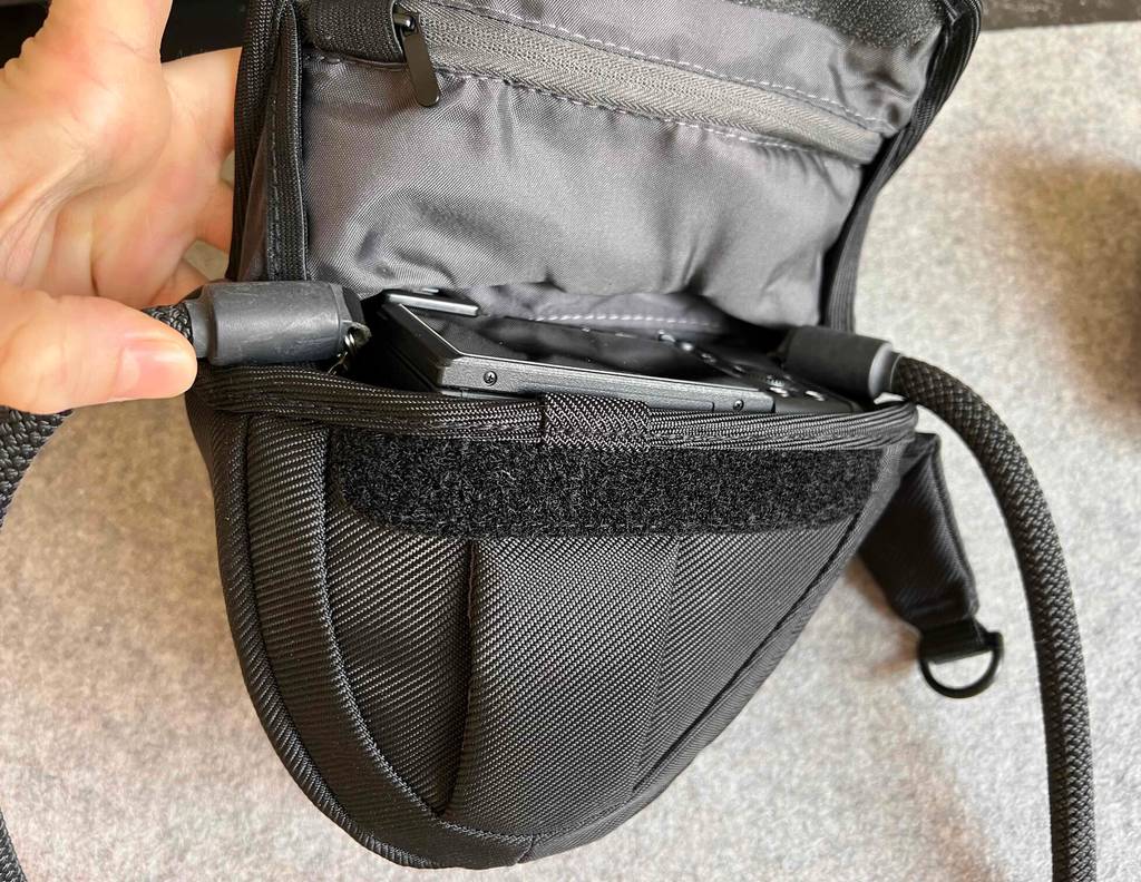 Eine Hand hält eine geöffnete, getestete Kameratasche, in der sich passgenau ein Fotoapparat befindet.