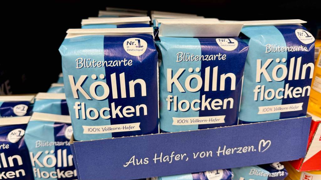Mehrere Packungen mit zarten, getesteten Kölln-Haferflocken befinden sich in einem Karton auf einem Verkaufsregal.