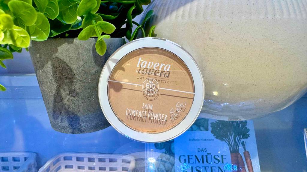 Das Naturkosmetik-Make-up im Test in der Dose mit transparentem Deckel steht auf einer Glasfläche.
