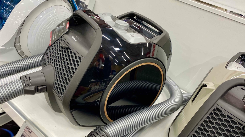 Ein Staubsauger ohne Beutel von der Seite auf einem Verkaufsregal zwischen weiteren Staubsaugern.