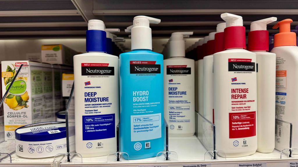 Ein blauer Spender mit getesteter Neutrogena-Bodylotion steht auf dem Regal eines Drogeriemarktes neben weiteren Produkten für gesunde Haut.