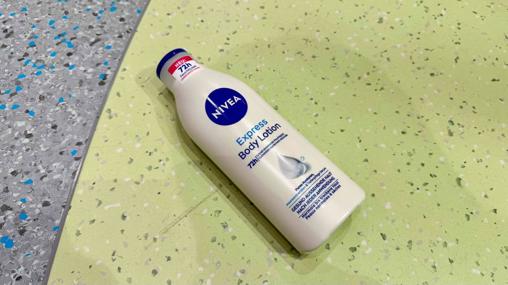 Eine weiße Flasche mit getesteter Nivea-Bodylotion liegt auf einem Linoleum-Boden.