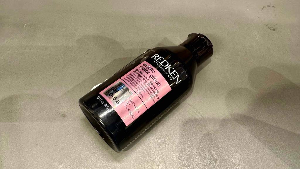 Redken-Shampoo-Test: Eine schwarze 300-ml-Kunststoffflasche liegt auf einer grauen Oberfläche.