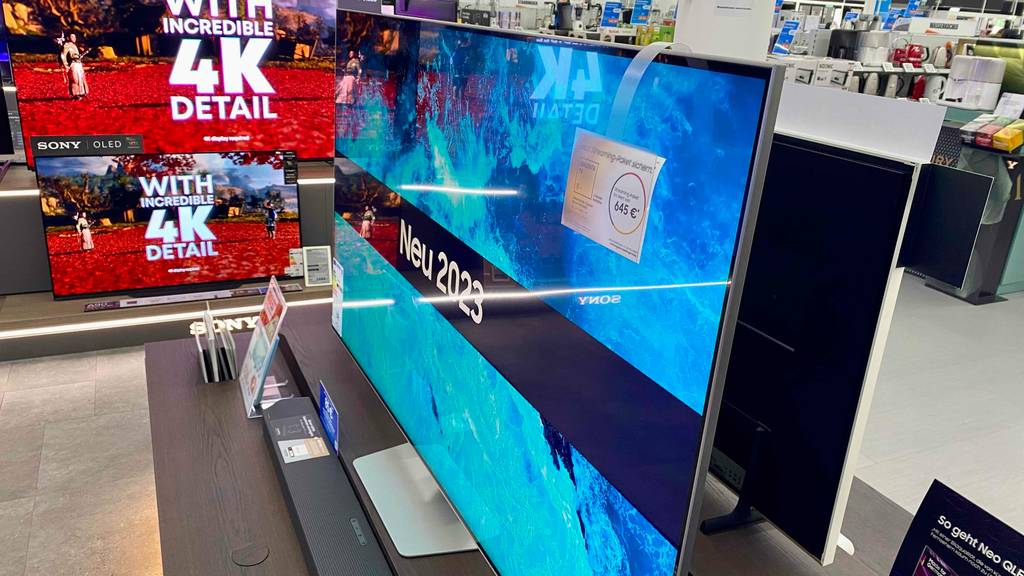 Mehrere Fernseher neben einem Samsung-Fernseher (65 Zoll) im Test, der sich eingeschaltet und inklusive Preis-Etikett in einem Geschäft befindet.