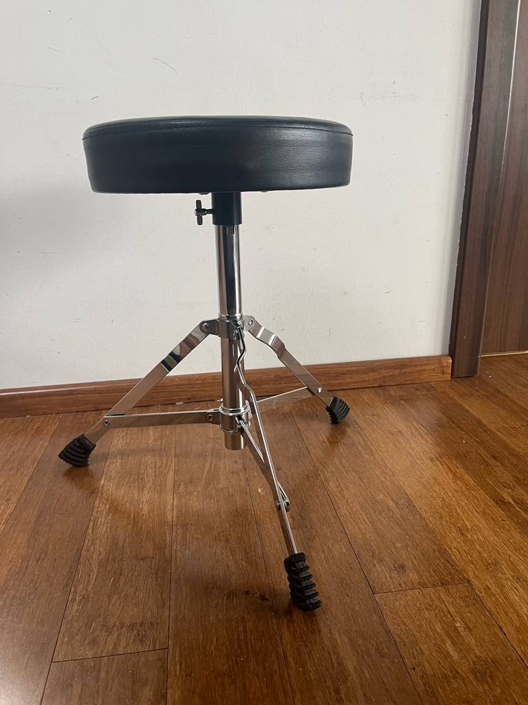 Ansicht von der Seite auf einen getesteten Schlagzeug-Hocker, der auf einem Holzboden steht.