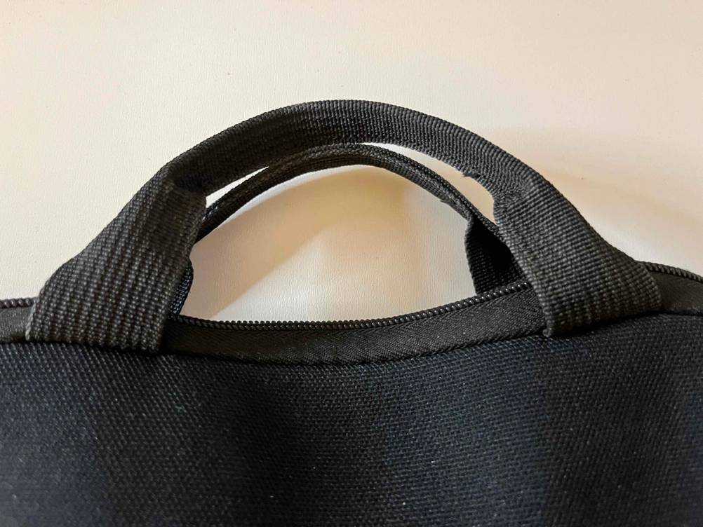 Nahaufnahme des verstärkten Handgriffs einer schwarzen Tablet-Tasche im Test, die aus schwarzem Gewebe gefertigt ist.