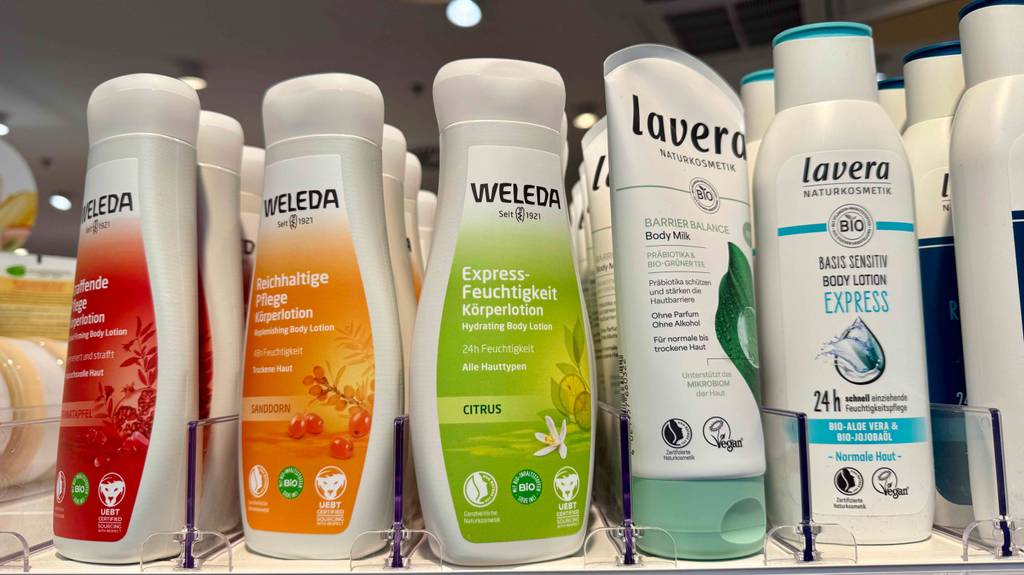 Getestet: Eine Kunststoffflasche mit WELEDA Bodylotion steht neben anderen Körperpflegeprodukten auf einem Regal im Drogeriemarkt.
