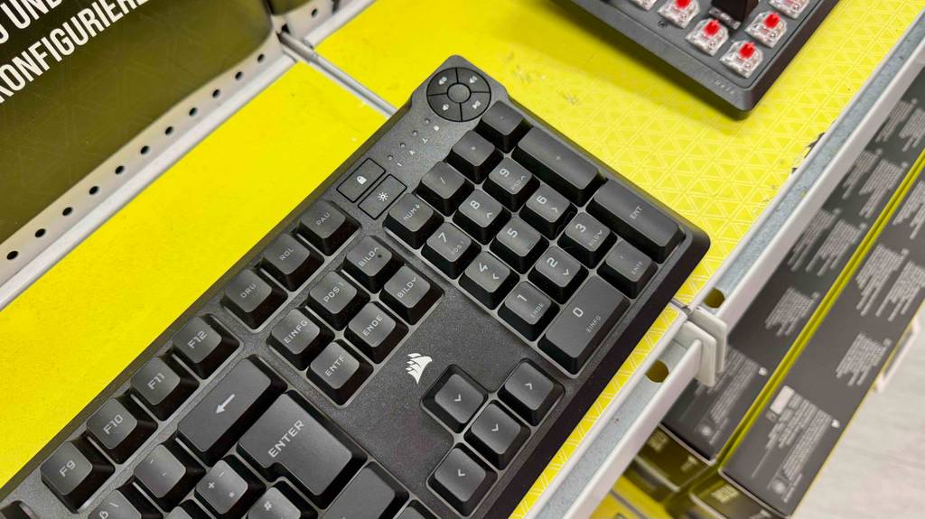 Detailansicht der schwarzen, getesteten Corsair-Tastatur auf einem gelben Ausstellungsregal.