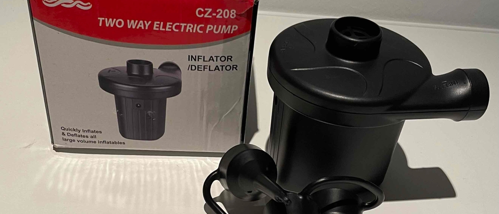 Getestete elektrische Luftpumpe liegt neben der Originalverpackung auf einer hellen Fläche.