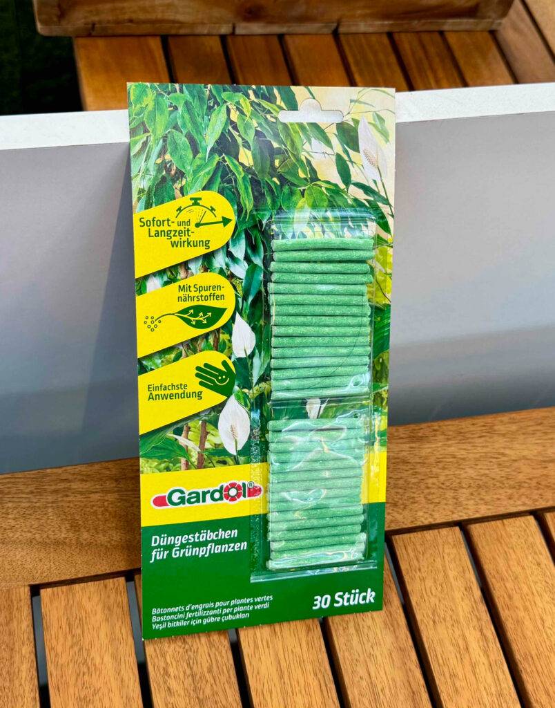 Dünger für Zimmerpflanzen im Test: Die Düngestäbchen in der 30-Stück-Verpackung stehen auf einer Holzfläche.