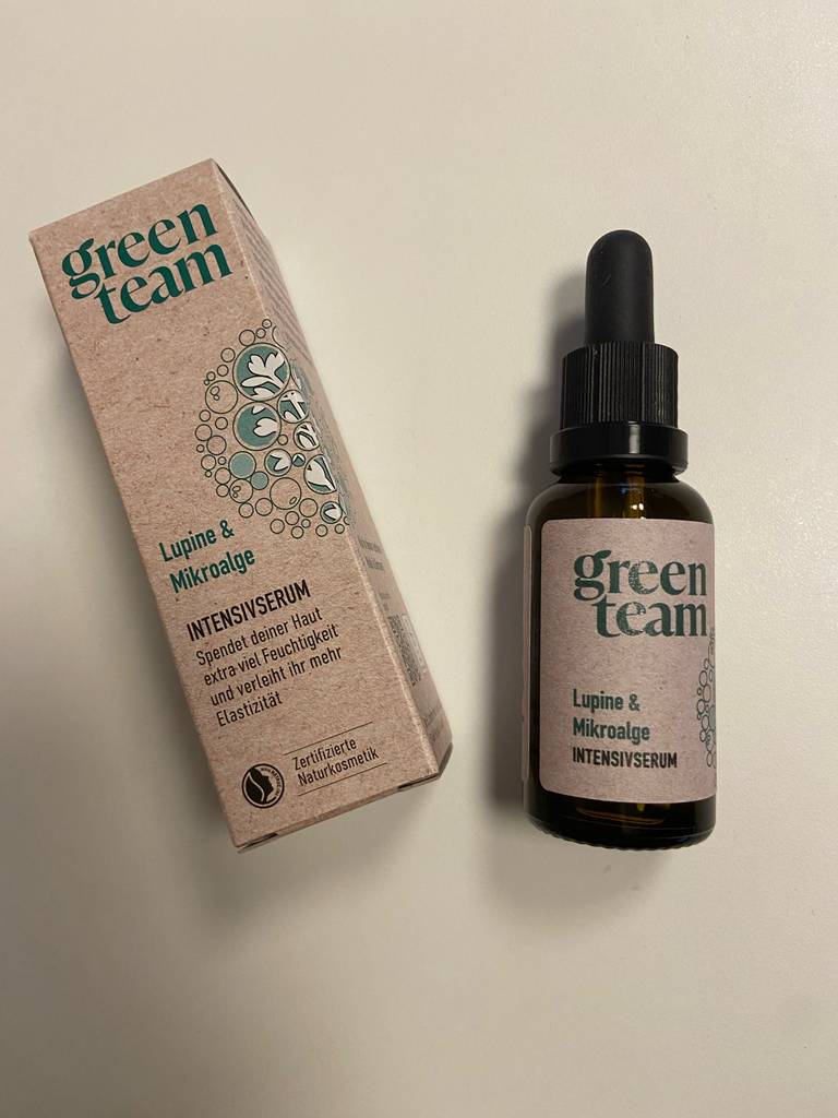 Eine Packung liegt neben der getesteten Glättungscreme in der braunen Flasche inklusive eines Pipetten-Schraubverschlusses.