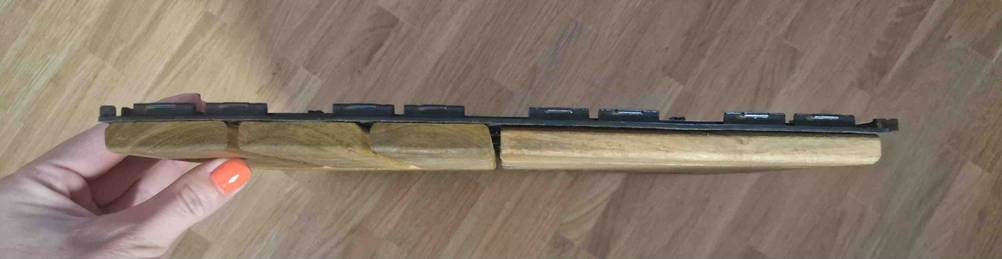 Hand hält eine getestete Holzfliese für Balkone, mit Fokus auf ihre Höhe.