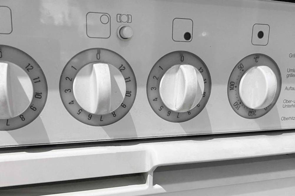 Backofen im Test: Detailaufnahme von vier Drehknopf-Reglern eines weißen Backofens.