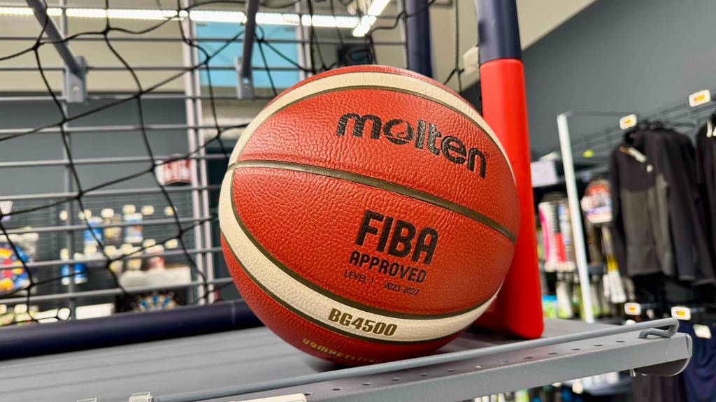 Der getestete Basketball in Rot mit beigefarbenen Streifen liegt auf einem Verkaufsregal.