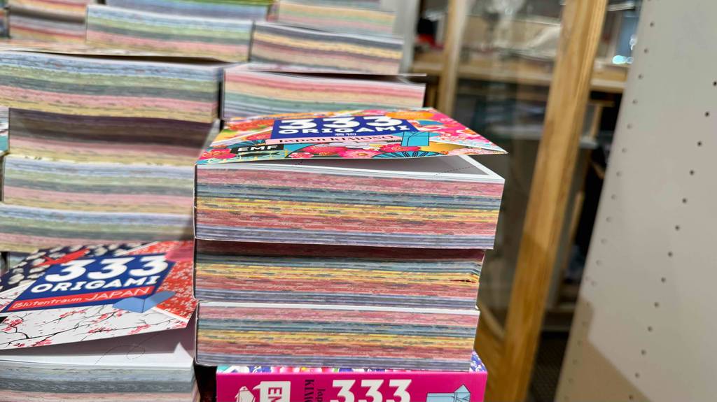 Nahaufnahme der gestapelten Bücher inklusive der 333 Seiten, auf denen sich die getesteten Origami-Papiere befinden.