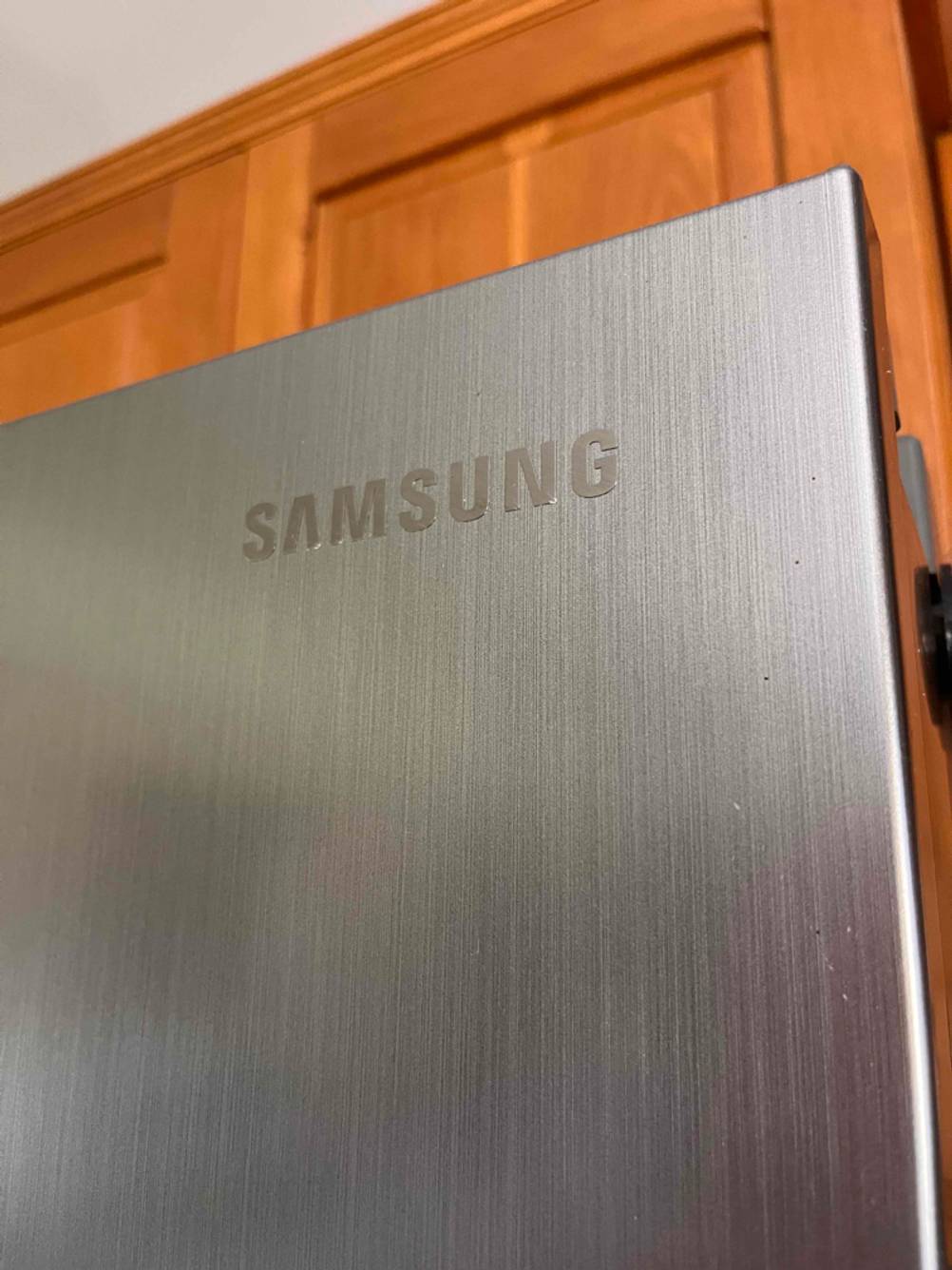 Standkühlschrank-Test: Detailaufnahme der rechten, oberen, vorderen Ecke eines metallfarbenen Kühlschranks mit dem Markenzeichen Samsung.