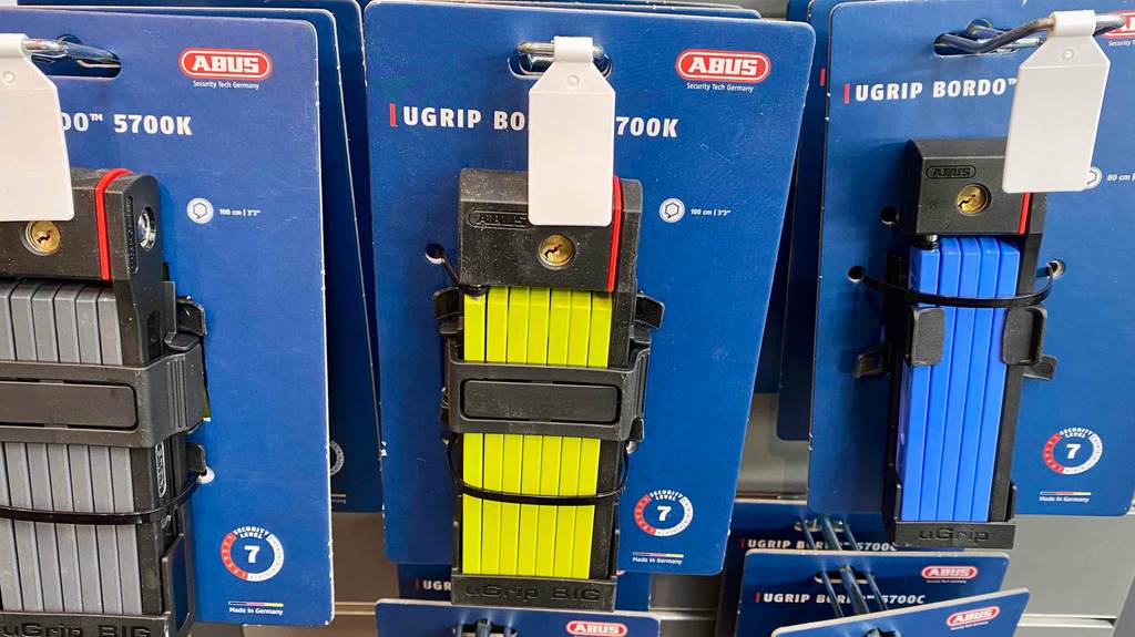 Mehrere Abus-Faltschlösser im Test befinden sich in ihren blauen Verpackungen am Verkaufsstand.