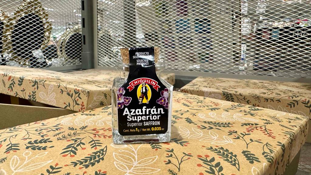 Das getestete Azafran-Gewürz in dem Glasbehälter inklusive Korken steht auf einer gemusterten Decke.