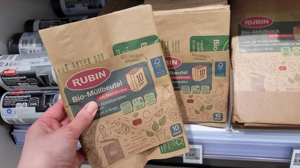 Eine Hand hält eine Verpackung mit 10 Stück Bio-Müllbeuteln im Test vor einem Verkaufsregal.