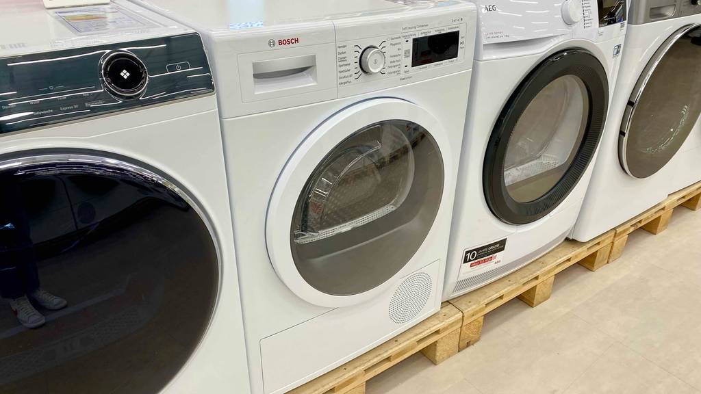 Im Test: Bosch-Wärmepumpentrockner zusammen mit anderen Frontladern in einem Ausstellungsbereich auf Holz-Paletten.