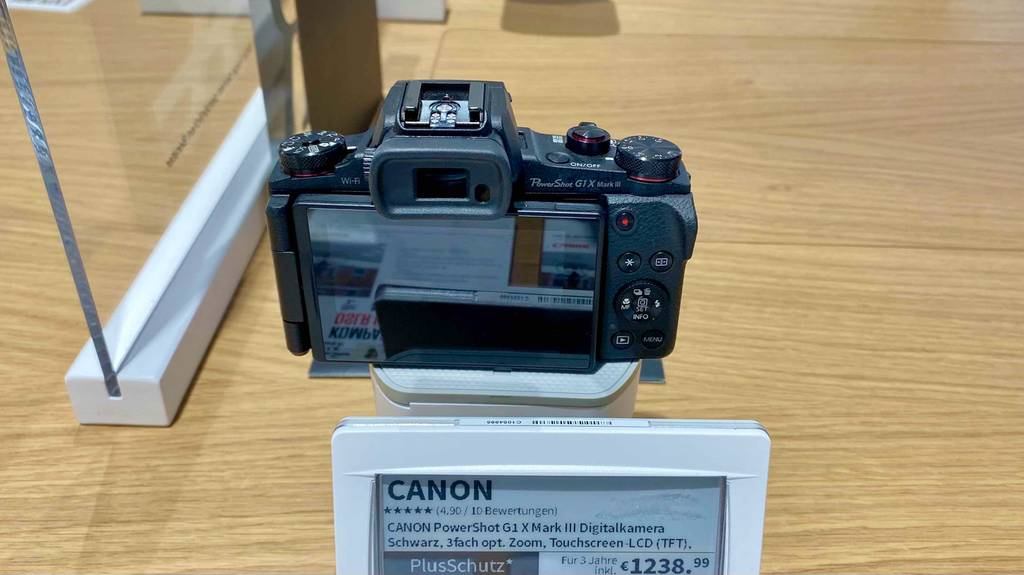 Ansicht von hinten auf das schwenkbare Display einer getesteten Canon-Digitalkamera mit Preisschild in einem Verkaufsbereich.