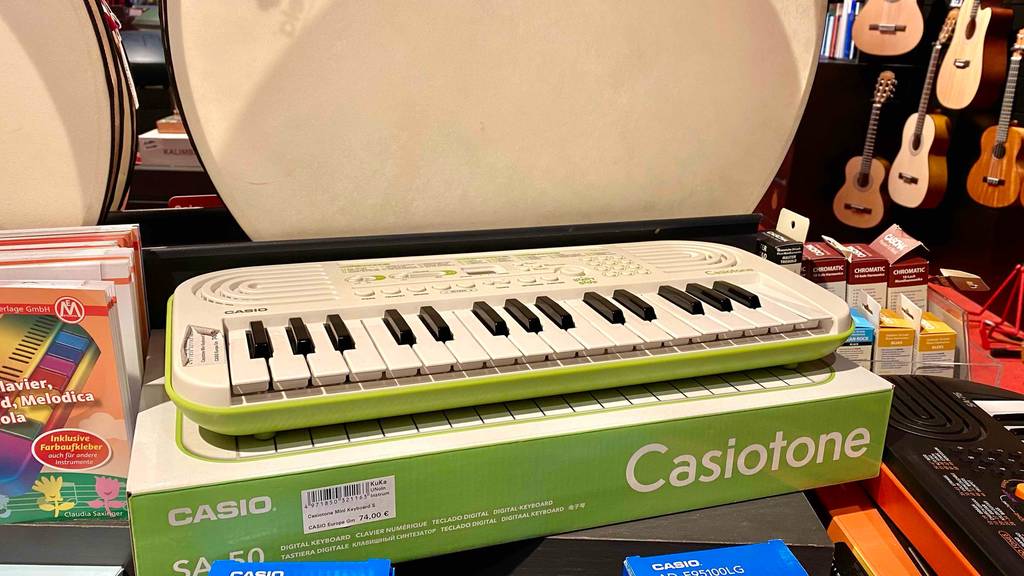 Im Test: ein Keyboard Casiotone in weiß-grünem Design der Marke Casio befindet sich auf seinem Originalkarton in einem Geschäft für Musikinstrumente.