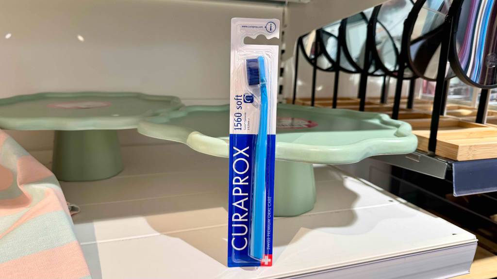 Im Test: Eine Curaprox-Zahnbürste steht in ihrer Verpackung auf einem Regal mit Küchenutensilien.
