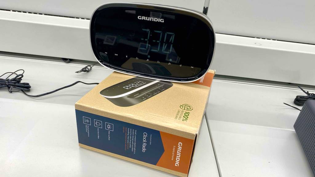 Ein getesteter DAB-Radiowecker der Marke Grundig befindet sich auf seiner Verpackung auf einem weißen Verkaufsregal.