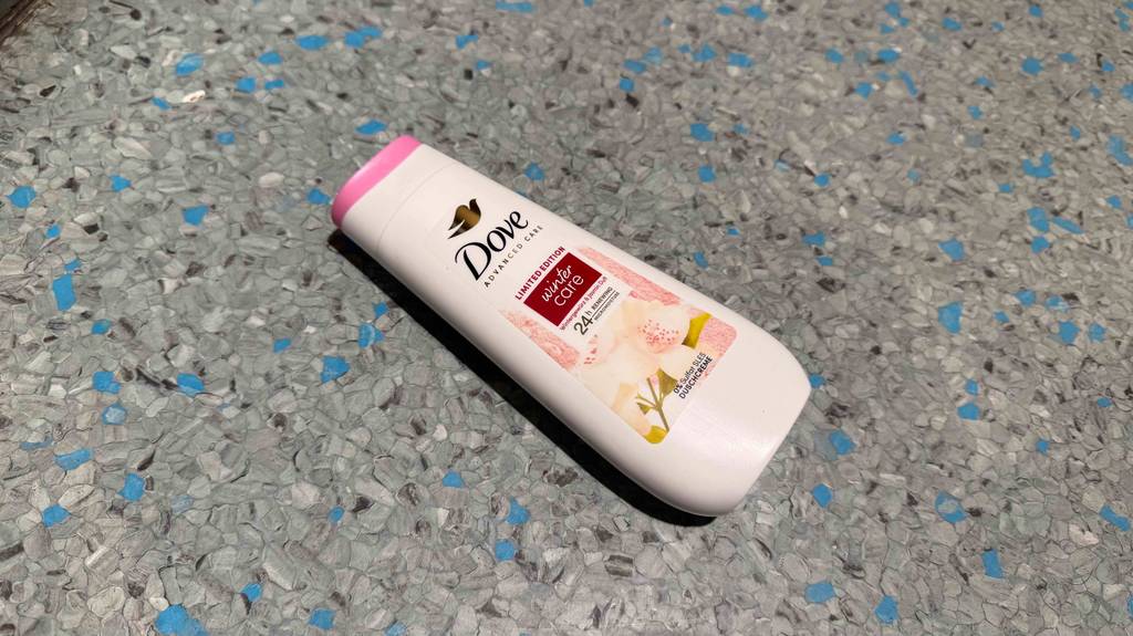 Eine weiße Kunststoff-Quetschflasche mit Dove-Duschgel im Test liegt auf einem Linoleumboden.