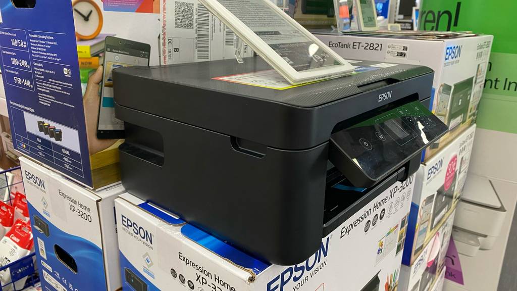 Drucker unter 100 Euro getestet: Ein Drucker befindet sich auf einer Verpackung mit einem Expression Home EP-3200 von Epson im Verkaufsbereich.