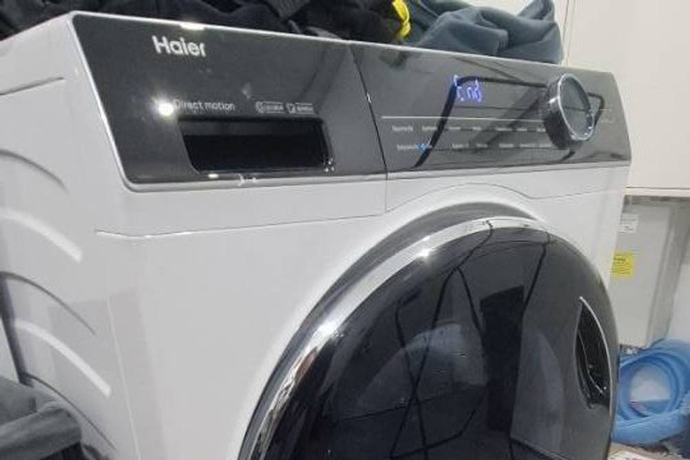 Haier-Waschmaschine im Test: auf einem Modell HW80-BI4978 stehen mehrere Waschpulver und Weichspüler.