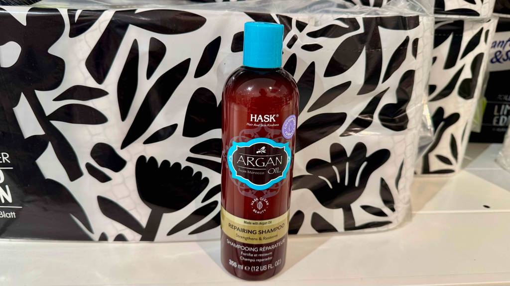 Eine Quetschflasche von Hask mit Shampoo im Test steht vor einer schwarz-weiß gemusterten Wand.